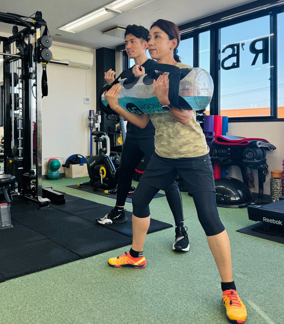 トレーナーが女性のお客様へトレーニング指導をしている様子