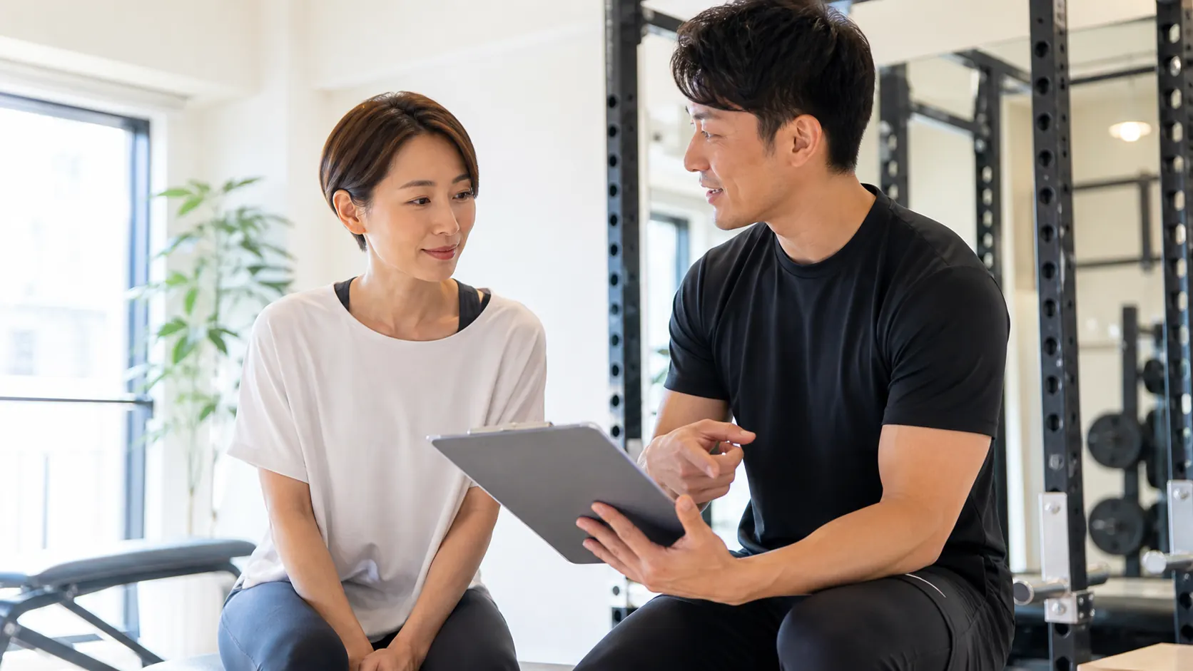 倉敷の個室ジムで料金プランをトレーナーと確認する日本人女性